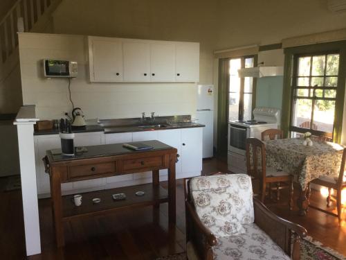 uma cozinha com um lavatório e uma mesa com uma cadeira em The Old School House em Te Awamutu