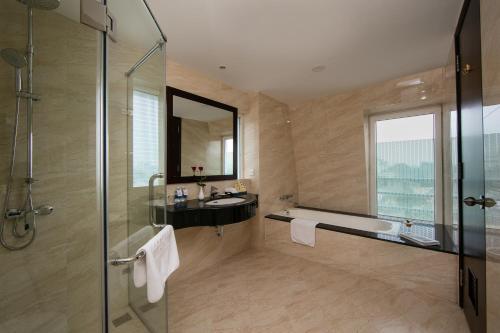 a bathroom with a shower and a tub and a sink at Zephyr Suites Boutique Hotel in Hanoi