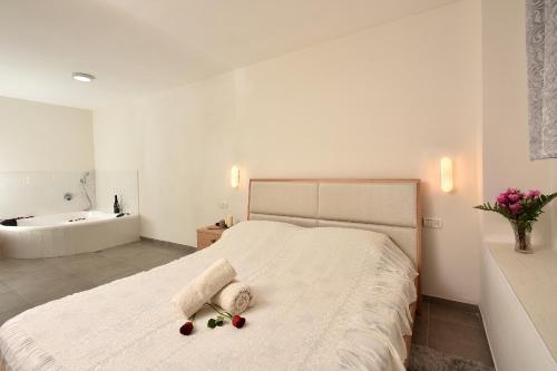 a white bedroom with a bed and a bath tub at Luxury Suite with Jaccuzzi & Heated Pool in Tiberias