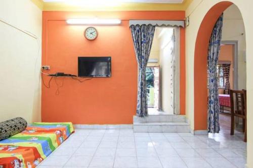 a living room with orange walls and a tv on the wall at Sudeep Bungalow in Alibaug
