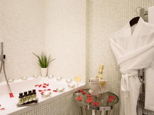 a bathroom with a tub and a glass table with wine bottles at B Montmartre in Paris