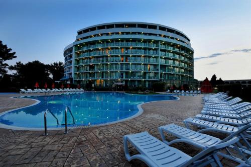 a large building with chairs and a swimming pool at Hotel Caesars Palace in Sunny Beach