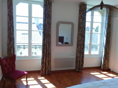 a bedroom with windows and a mirror and a chair at L'AURE BLEUE in Bayeux