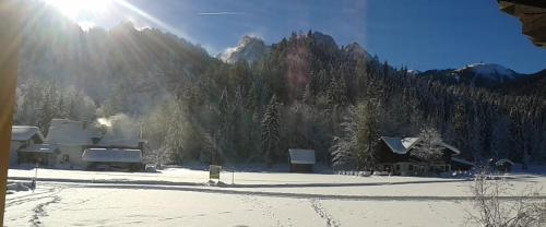 a house in the snow with the sun in the background at Ferienwohnung Peter Egger in Gosau