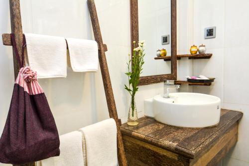 ein Badezimmer mit einem Waschbecken, einem Spiegel und Handtüchern in der Unterkunft Hotel Queen Jamadevi in Mawlamyaing