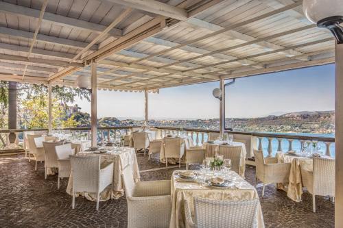 a restaurant with tables and chairs and a view of the water at Hotel Castel Vecchio in Castel Gandolfo