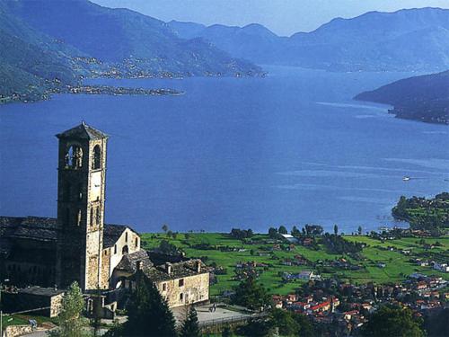 a building with a clock tower next to a body of water at Hotel Riviera in Griante Cadenabbia