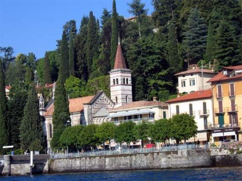 a building on the side of a river with a church at Hotel Riviera in Griante Cadenabbia