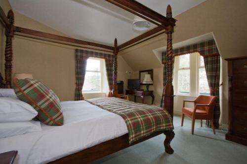 a bedroom with a bed and a desk and two windows at Loch Kinord Hotel in Dinnet