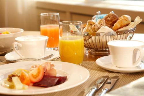 a table with a plate of breakfast foods and orange juice at Oberwaid - Das Hotel. in St. Gallen