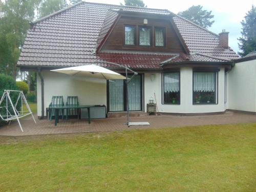 a house with a patio with an umbrella and a swing at Ferienhaus Emmelie in Senzig