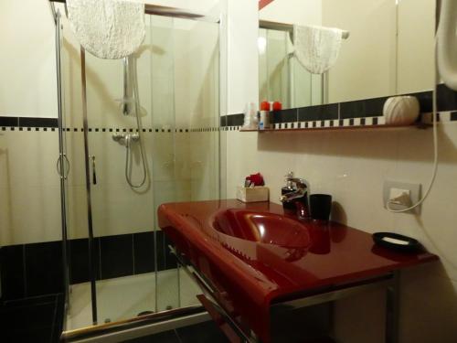 La salle de bains est pourvue d'un lavabo rouge et d'une douche. dans l'établissement I Fiori di Malpensa, à Ferno