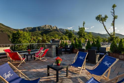 a patio with chairs and tables with mountains in the background at Hotel Logos in Zakopane