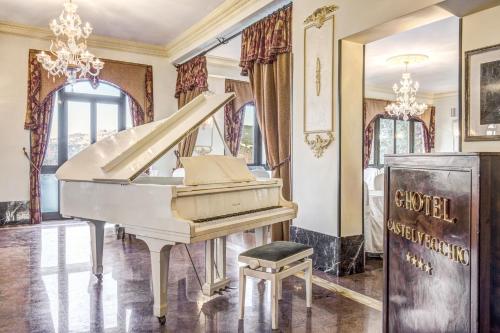 a white piano in a room with a chandelier at Hotel Castel Vecchio in Castel Gandolfo