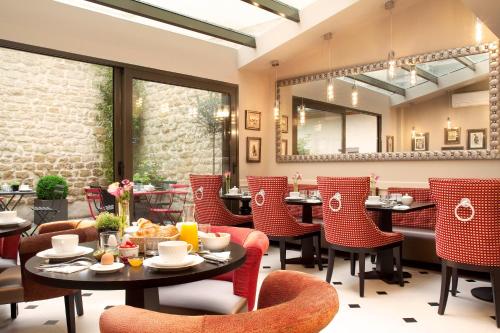 a restaurant with red chairs and tables and a mirror at Hôtel des Comédies in Paris