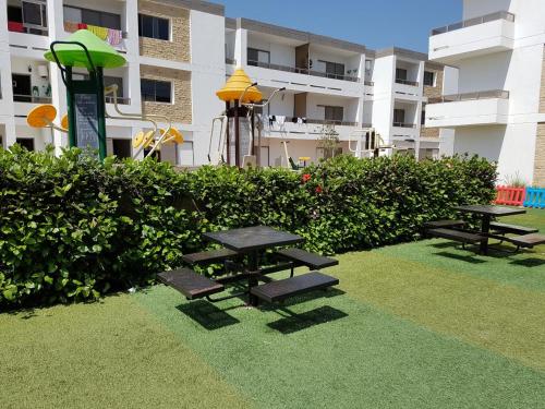 un grupo de mesas de picnic frente a un edificio en Marbella Beach Residency, en Minaret de Mansuria