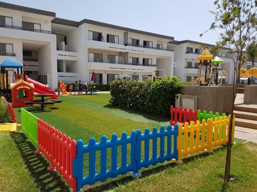 un parque infantil con una valla colorida frente a un edificio en Marbella Beach Residency, en Minaret de Mansuria