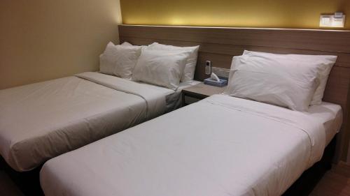 two beds in a hotel room with white sheets and pillows at Star Tree Homestay -Contactless Self Check in in Kuantan
