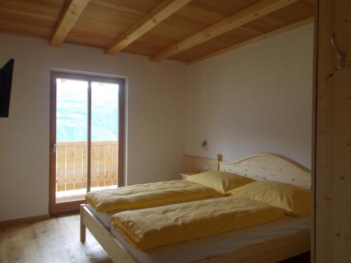 two beds in a bedroom with a large window at Pichlerhof in Bressanone