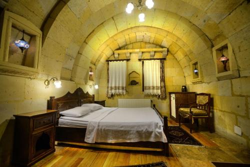 Un dormitorio con una cama en una habitación de piedra. en Vineyard Cave Hotel, en Göreme