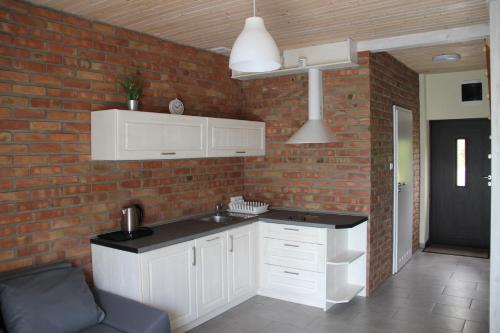 uma cozinha com armários brancos e uma parede de tijolos em Apartamenty Wisełka em Międzyzdroje