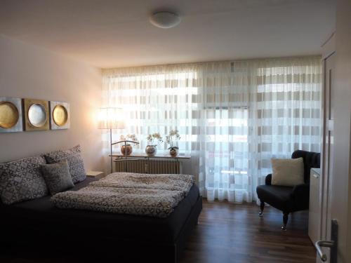 a bedroom with a bed and a chair and a window at Schnuckelig und Fein in Oberstaufen