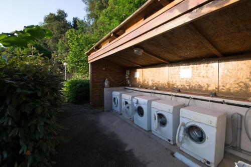 une rangée de lave-linge sous un bâtiment dans l'établissement Sarl Aurore-Vacances, à Vico