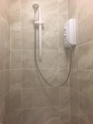 a shower with a phone on a tiled wall at Townhouse @Richmond Street Stoke in Stoke on Trent