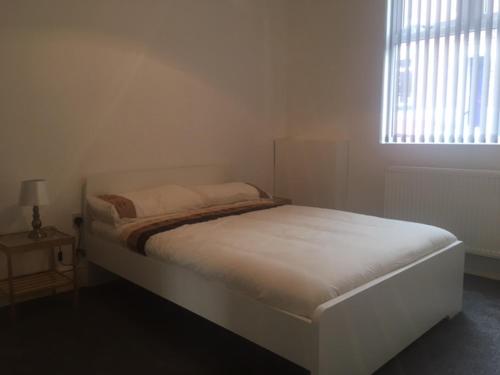 Cama blanca en habitación con ventana en Townhouse @Richmond Street Stoke, en Stoke on Trent