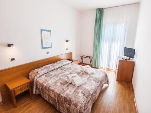 a hotel room with two beds and a television at Hotel Palazzuolo in San Quirico dʼOrcia