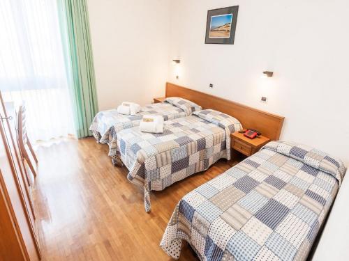 a room with two beds and a table in it at Hotel Palazzuolo in San Quirico dʼOrcia