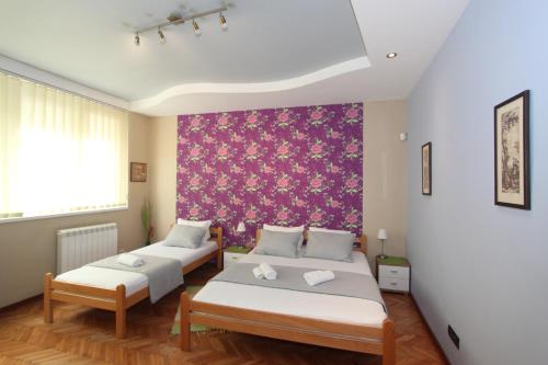 a bedroom with two beds and a pink wall at Sneki Apartment in Belgrade