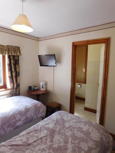 a bedroom with a bed and a tv on the wall at The Railway Inn in Forden