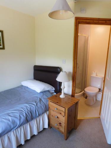 a bedroom with a bed and a bathroom with a toilet at The Railway Inn in Forden