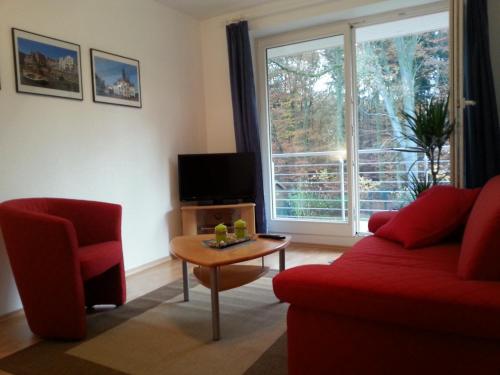 a living room with a red couch and a table and a window at Ferienwohnung an der Hasenburg in Lüneburg
