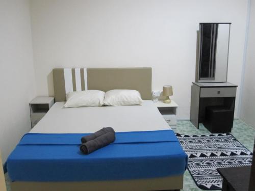 Al-Kahfi Homestay في دونجون: غرفة نوم بسرير من اللون الازرق والابيض