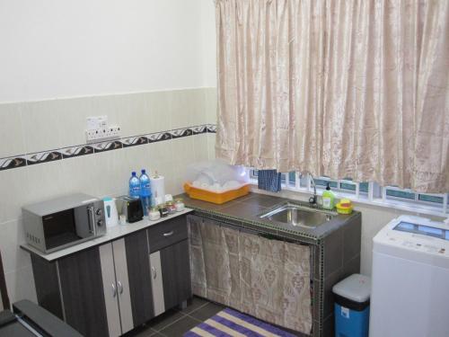 eine kleine Küche mit einer Spüle und einer Mikrowelle in der Unterkunft Al-Kahfi Homestay in Dungun