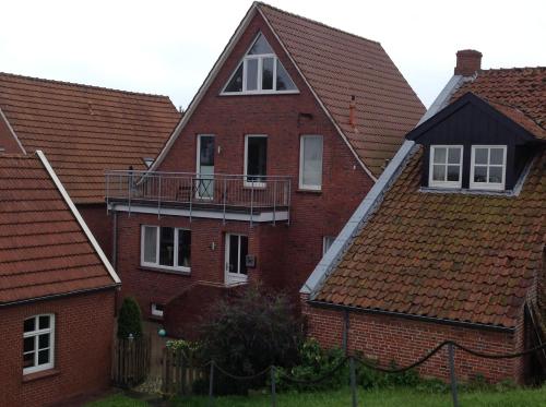 a red brick house with a balcony in between two houses at Vier Sterne am Hafen, Ditzum in Ditzum