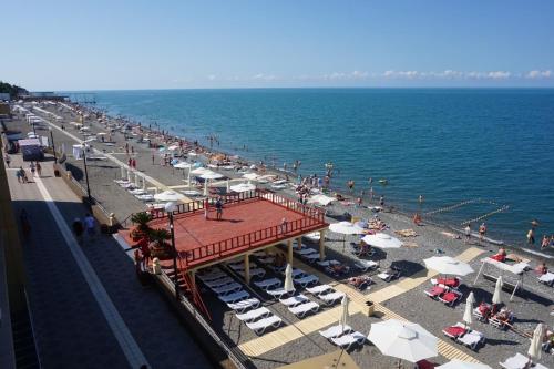 einen Strand mit Liegestühlen und Sonnenschirmen und dem Meer in der Unterkunft Lazur Beach by Stellar Hotels, Adler in Adler