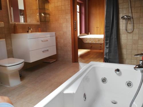 Lujoso duplex en Port del Comte في La Coma i la Pedra: حمام مع حوض استحمام أبيض ومرحاض