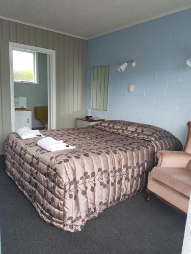 ヘイスティングズにあるCamberley Court Motelの大きなベッドと椅子のある寝室