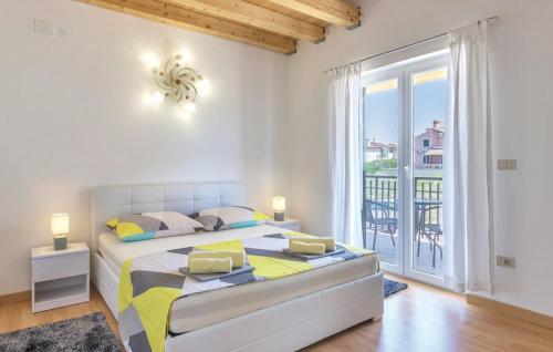 a white bedroom with a large bed and a balcony at Istriana house in Banjole