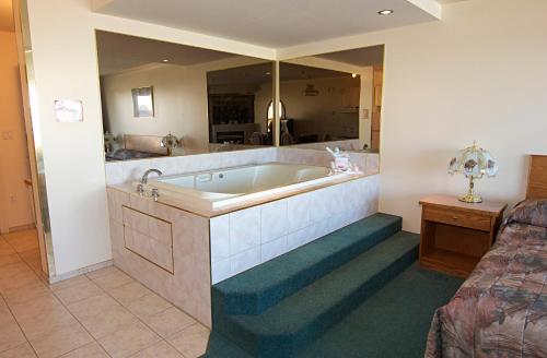 a large bathroom with a tub and a bed at Western Budget Motel Bonnyville in Bonnyville