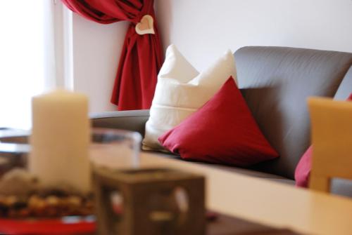 a couch with red and white pillows on it at Mason La Zondra in Vigo di Fassa