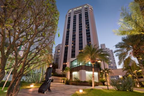 a man standing in a park in front of a tall building at Ninety Hotel in Sao Paulo