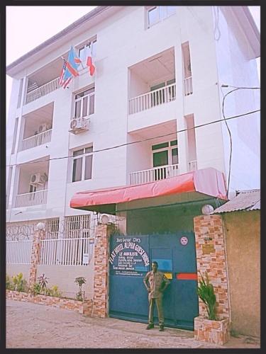 a man standing in front of a building at Flat Hôtel Alpha in Kinshasa