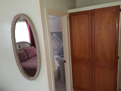 a mirror on a wall next to a bathroom at Apartment Unforgetable Gardens in Falmouth