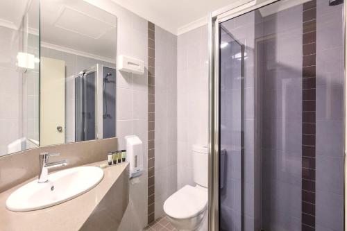 uma casa de banho com um WC, um lavatório e um chuveiro em Garden City Hotel, Best Western Signature Collection em Canberra
