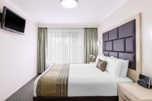 a hotel room with a large bed and a television at Garden City Hotel, Best Western Signature Collection in Canberra