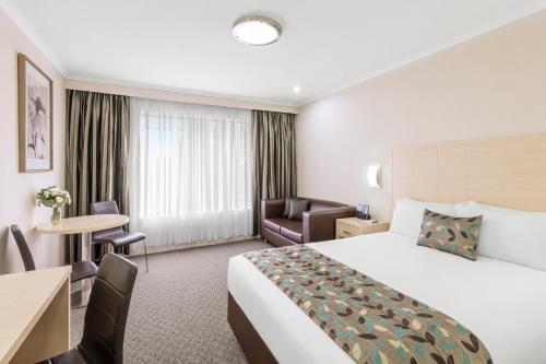 a hotel room with a king sized bed and a desk at Garden City Hotel, Best Western Signature Collection in Canberra